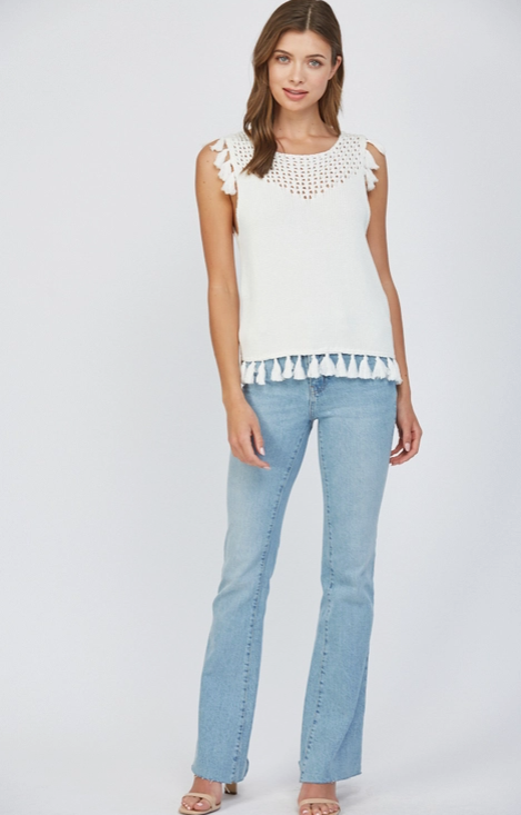 Woman wearing a white top with floral details and light blue jeans on a white background